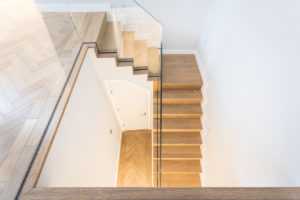 wooden staircase with glass panel bannister