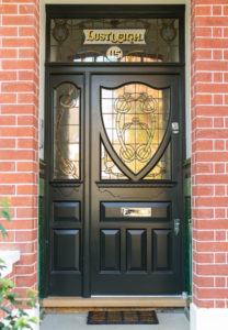 artisan woodwork on black door with stained glass windows