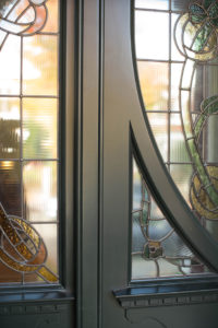artisan woodwork on black door with stained glass windows