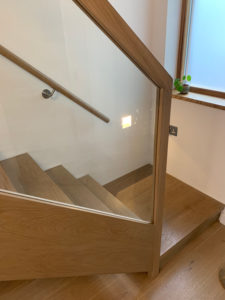 wooden staircase with glass window bannister
