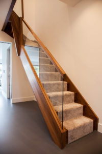 wooden staircase with glass panel window and handrail