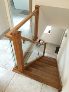 wooden staircase with glass panel window and handrail